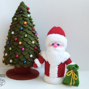 May include: A knitted Santa Claus doll with a white beard and red suit holds a green bag. A green knitted Christmas tree with colorful ornaments stands next to him.