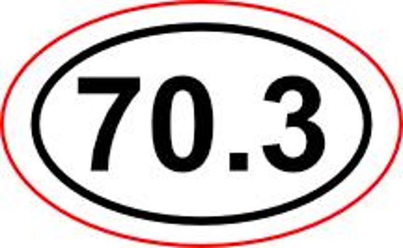 May include: Oval sticker with the number "70.3" in bold black font, centered within a black oval, which is then surrounded by a red oval border. The design is simple and clear, suitable for various applications.