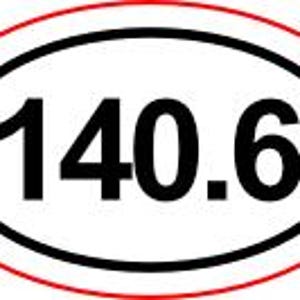 May include: An oval sticker with the number 140.6 in bold, black font. The number is centered within a black oval, which is surrounded by a red oval border. The sticker is likely for a vehicle or equipment.