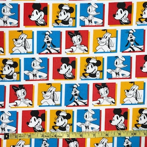 May include: A white fabric with a repeating pattern of cartoon characters in colorful squares. The characters include Mickey Mouse, Minnie Mouse, Donald Duck, and Goofy. The fabric is perfect for quilting, sewing, and crafting.
