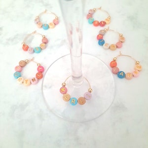 May include: Set of six colorful glass charms with gold wire hoops. Each charm has a different name spelled out in gold letters on colorful beads. The names are:  Suzy,  Katie,  Kelly,  Ellie,  Anne, and  Karli.