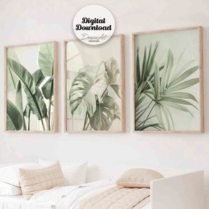 Puede incluir: Tres láminas botánicas enmarcadas con hojas tropicales verdes, en marcos de madera clara. Cuelgan sobre una cama blanca con ropa de cama beige. La imagen incluye el texto "Digital Download" y el nombre del artista.