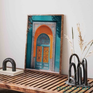 May include: A framed print of a colorful archway with a teal blue background, orange arch, and a blue and yellow patterned door. The archway is decorated with intricate tile work.