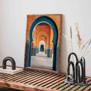 May include: A framed photograph of a colorful archway in a Moroccan building. The archway is made of blue and yellow tiles and leads to a courtyard with a blue door.