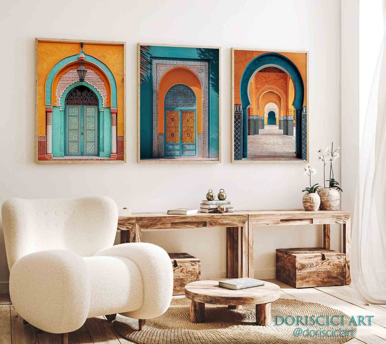 May include: Three framed prints of colorful archways in a Moroccan style. The prints are hung on a white wall above a wooden table with a white armchair and a wooden coffee table.