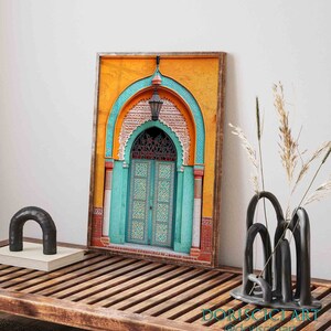 May include: A framed print of a colorful, ornate doorway with a teal archway and a wooden door with intricate carvings. The door is set against a yellow background with geometric patterns.