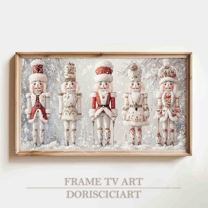 Pode incluir: Impressão emoldurada com cinco figuras decorativas de quebra-nozes em uma cena de inverno nevada. Os quebra-nozes usam uniformes vermelhos, brancos e dourados, cada um segurando um bastão. O texto "FRAME TV ART DORISCIART" está na parte inferior.