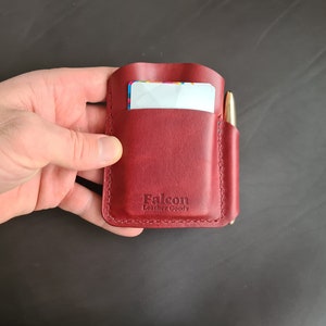 May include: A burgundy leather wallet with a pen holder and a card slot. The wallet has the text "Falcon Leather Goods" embossed on the front.