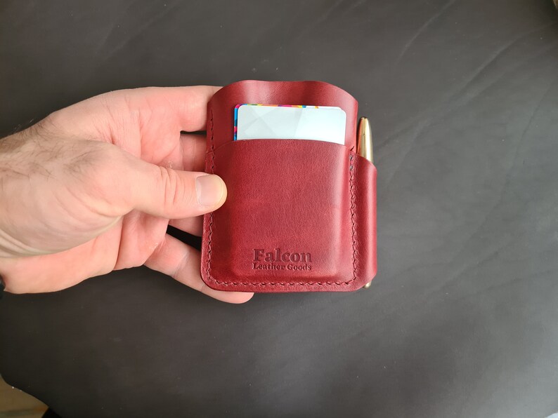 May include: A burgundy leather wallet with a pen holder and a card slot. The wallet has the text "Falcon Leather Goods" embossed on the front.