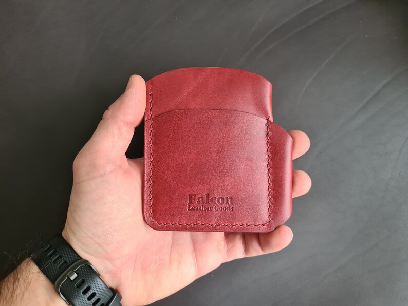 May include: A burgundy leather wallet with the text "Falcon Leather Goods" embossed on the front.