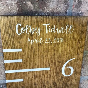 May include: A wooden growth chart with white markings and the name "Colby Tidwell" and the date "April 23, 2018" written on it. The number "6" is also visible on the chart.