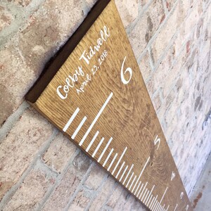 May include: A wooden growth chart with white markings and numbers. The chart is personalized with the name "Colby Tidwell" and the date "April 23, 2018".