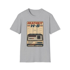 Könnte beinhalten: Ein kurzärmeliges T-Shirt in Grau meliert mit einem Grafikdruck eines alten Heathkit H-8 Personal Computers. Das Design enthält technische Schaltpläne, den Text HEATHKIT H-8 und 8-BIT PERSONAL COMPUTER in einem rechteckigen Retro-Rahmen.