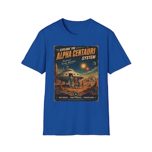 May include: A royal blue short-sleeve t-shirt featuring a retro-style graphic print. The design depicts a space scene with a flying saucer, a family of four, and the text "EXPLORE THE ALPHA CENTAURI SYSTEM" along with "Tomorrow's Family Adventure".