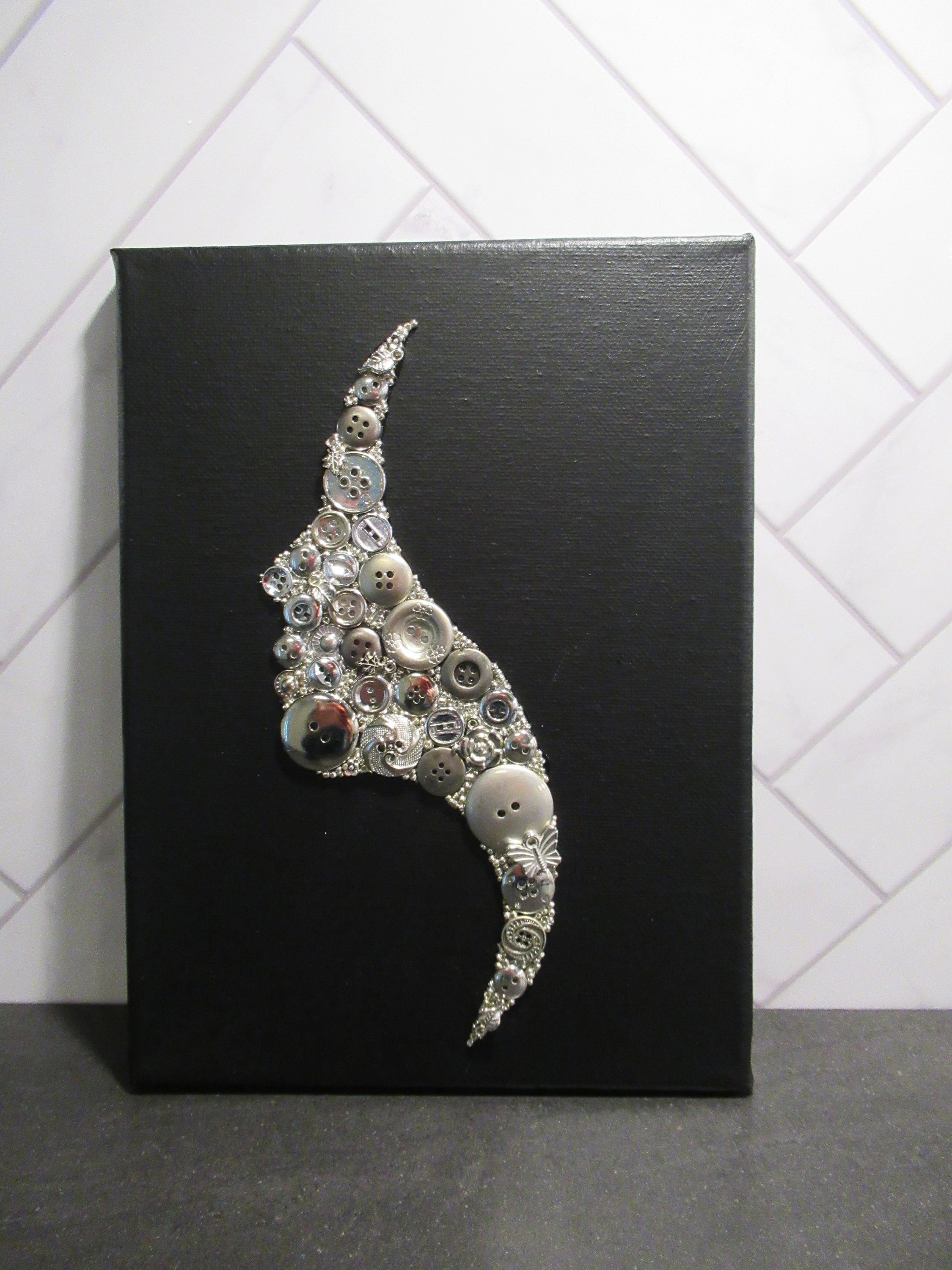 Button art painting silver silhouette woman face, on black painted canvas