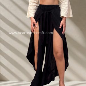 Puede incluir: Un top corto color crema de manga larga con la parte delantera anudada, combinado con pantalones negros con perneras divididas. Los pantalones tienen cintura alta y cierre de lazo. El sitio web www.heartearthcraft.com es visible.