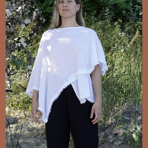May include: A white, asymmetrical, lightweight poncho with a frayed edge. The poncho is made of a soft, breathable fabric and has a relaxed fit.
