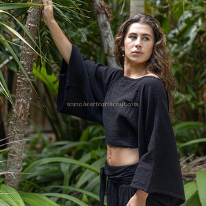 May include: A black cropped top with wide, loose-fitting sleeves and a textured fabric finish. The garment features a round neckline and a boxy silhouette. The text www.heartearthcraft.com is printed in white across the center of the black fabric.