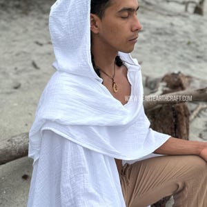 Pu&ograve; includere: Un capo bianco con cappuccio in tessuto testurizzato. Il capo &egrave; indossato da una persona con i capelli castani e una collana. Il testo "www.heartearthcraft.com" &egrave; visibile nell'angolo in basso a destra dell'immagine.