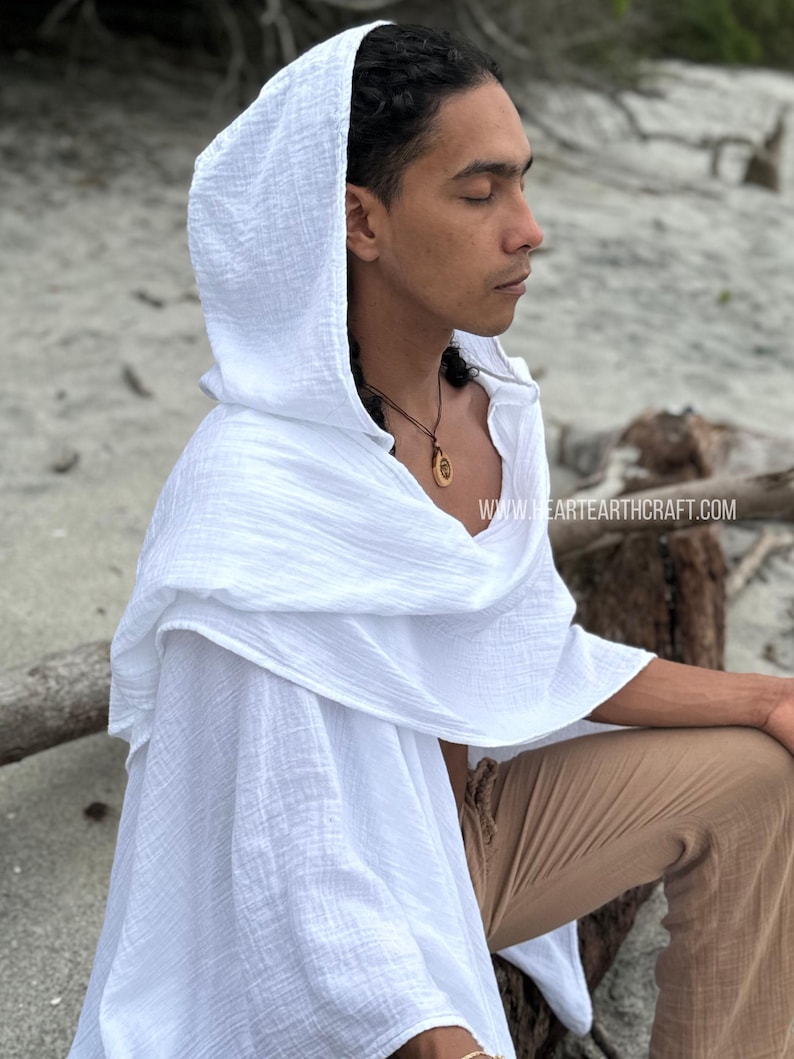 Pu&ograve; includere: Un capo bianco con cappuccio in tessuto testurizzato. Il capo &egrave; indossato da una persona con i capelli castani e una collana. Il testo "www.heartearthcraft.com" &egrave; visibile nell'angolo in basso a destra dell'immagine.