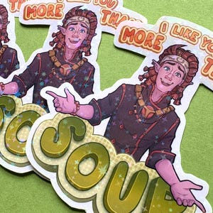May include: Holographic stickers featuring a cartoon character with pointed ears, wearing a dark brown outfit with star accents and a gold necklace. The stickers have the text "I LIKE YOU MORE THAN SOUP" in a layered, bubbly font.