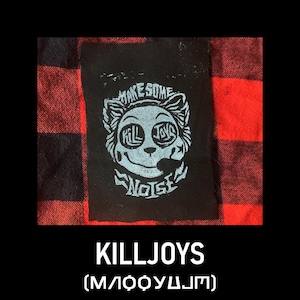 May include: Black patch featuring a light blue cartoon face design with the words "MAKE SOME NOISE" and "KILLJOYS". The patch is set against a red and black plaid background. The word "KILLJOYS" is printed below the patch.