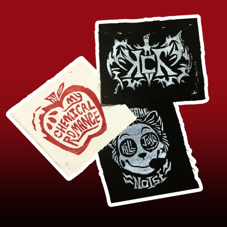 May include: Three square patches with white borders. One is off-white with a red apple design and the text "My Chemical Romance". Two are black with silver designs and text. One says "ICK" and the other says "Kill Joy Noise".
