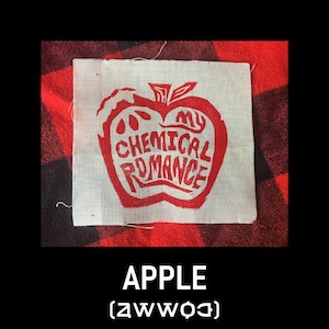 May include: A square, off-white patch with a red apple design and the words "My Chemical Romance". The patch is on a red and black plaid background, with the word "APPLE" and a symbol below.