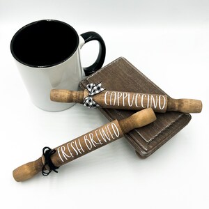 May include: Two wooden rolling pins with black and white ribbon accents. One rolling pin says "Fresh Brewed" and the other says "Cappuccino".