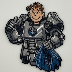 May include: Embroidered patch featuring a cartoon character in gray power armor, holding a tattered blue cloth. The character has brown hair and a smiling face. The armor has a blue emblem on the chest.