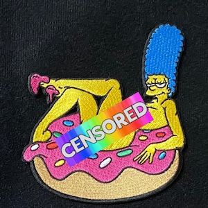 May include: Embroidered patch featuring a cartoon character with blue hair, yellow skin, and pink shoes, reclining on a pink donut with sprinkles. The word "CENSORED" is across the image in rainbow colors. The patch is on a black background.