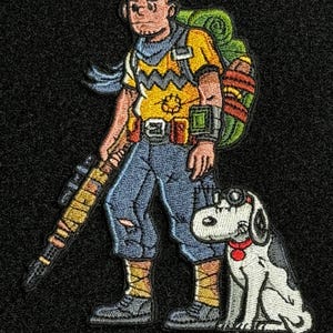 May include: Embroidered patch featuring a cartoon character with a backpack, rifle, and dog. The character wears a yellow shirt with a zig-zag pattern, blue pants, and boots. The dog is white with black spots and a red collar.