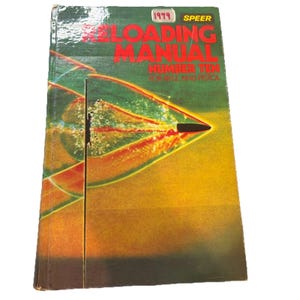 May include: Vintage "Reloading Manual Number Ten for Rifle and Pistol" book. The cover features a graphic of a bullet in flight with red and green streaks against a yellow and green background. The book is from 1979.
