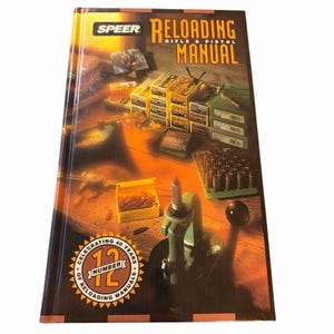 May include: Speer Reloading Rifle & Pistol Manual, Number 12, celebrating 40 years of reloading manuals. The cover features a detailed illustration of reloading equipment and components, with a wooden table background.