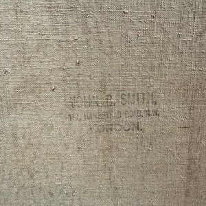 May include: Close-up of a textured, beige canvas. Faintly printed in black ink are the words "JOHN R. SMITH, 10, 11 CASTLE ST. OXFORD ST. LONDON."