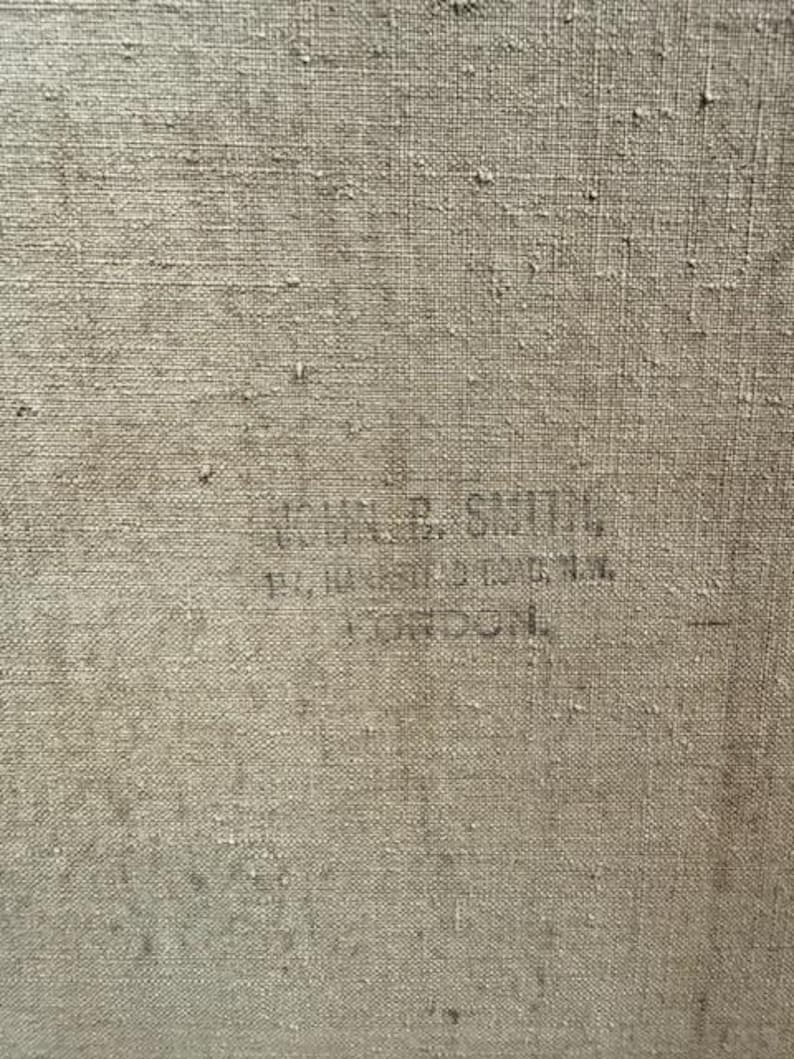 May include: Close-up of a textured, beige canvas. Faintly printed in black ink are the words "JOHN R. SMITH, 10, 11 CASTLE ST. OXFORD ST. LONDON."