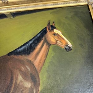 May include: Oil painting of a brown horse with a black mane and a white stripe on its face. The horse is set against a green background and framed in a gold ornate frame. The artwork is a portrait of the horse.