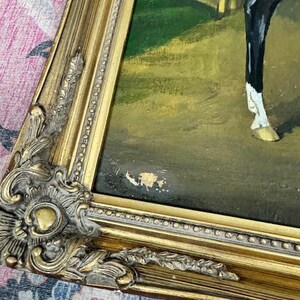May include: An antique oil painting of a horse in a stable, framed in a gold ornate frame. The painting features a brown horse with black legs and a white marking on its leg. The frame has intricate details and a distressed finish.