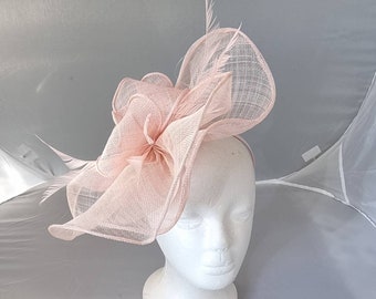 May include: A blush pink fabric headband with a large, layered flower design. The flower is made of a delicate, sheer fabric and has a ruffled texture.