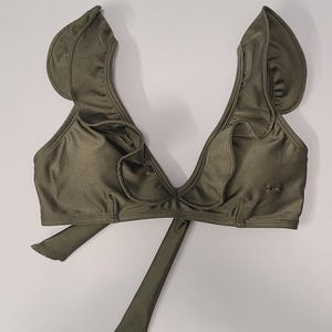 May include: A green bikini top with ruffled straps and a plunging neckline. The top ties at the back.