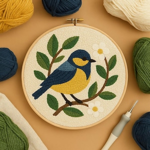 Pode incluir: Uma arte de bordado de agulha perfurada concluída com um pássaro azul e amarelo empoleirado em um galho com folhas verdes e flores brancas. O pássaro está centrado em um fundo creme. O aro de madeira é cercado por fios de várias cores.