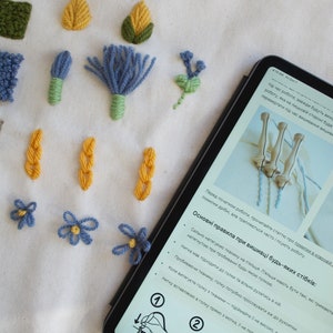 May include: A close-up of a tablet screen displaying instructions for embroidery. The text is in Ukrainian and includes the phrase "Basic rules for embroidery of any stitches". The screen shows a hand holding a needle and thread, demonstrating the steps of embroidery.