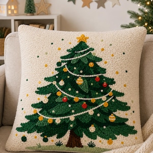 Puede incluir: Un cojín cuadrado con una base texturizada de color crema que presenta un diseño central de aguja perforada de un árbol de Navidad verde. El árbol está decorado con pequeños adornos rojos y amarillos, una guirnalda blanca y una estrella amarilla.
