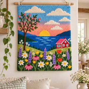 Puede incluir: Un tapiz rectangular hecho con técnica de aguja mágica que muestra un paisaje con un sol amarillo brillante sobre un lago azul, una casa roja, un árbol con flores rosas y un primer plano lleno de flores moradas, blancas y rosadas.