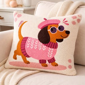May include: Square decorative pillow with a whimsical illustration of a dachshund wearing a pink sweater, beret, and sunglasses. The dog is walking on a pink path, set against a cream-colored background with pink accents. A cozy home decor item.