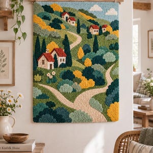 Puede incluir: Un tapiz rectangular de punch needle que muestra un paisaje con colinas verdes, caminos sinuosos de color beige y varias casas pequeñas con techos rojos. El arte textil texturizado incluye grupos de árboles amarillos, verde azulado y verdes.