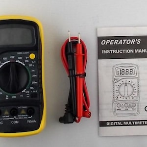 May include: A black and yellow digital multimeter with a dial and display screen, accompanied by red and black test leads and an instruction manual. The manual reads "OPERATOR'S INSTRUCTION MANUAL" and "DIGITAL MULTIMETER".