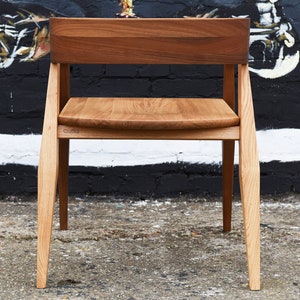 May include: A wooden chair with a light brown seat and a dark brown back. The chair has a simple design with straight legs and a slightly curved back.