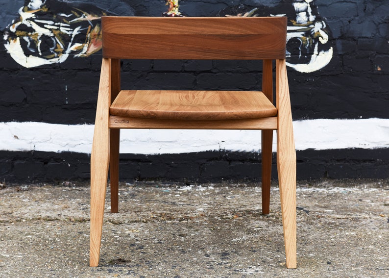 May include: A wooden chair with a light brown seat and a dark brown back. The chair has a simple design with straight legs and a slightly curved back.