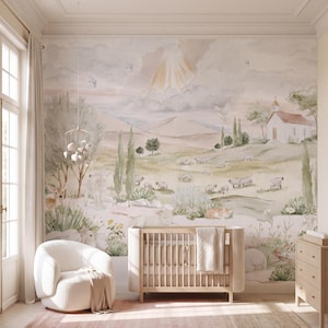 May include: A wall mural featuring a watercolour landscape with rolling hills, a small white church, grazing sheep, and a deer. The scene includes tall cypress trees, wildflowers, and a soft sky with sunbeams. A wooden crib and white chair are in front.